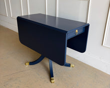 Load image into Gallery viewer, Classic Federal-inspired styling meets a fresh designer finish in this beautifully restored vintage drop leaf table. Professionally lacquered in Sherwin-Williams Naval, this versatile piece features two drop leaves that transform it from a slim console into a generous dining, game, or entry table in seconds. A single center drawer provides convenient storage, while the freshly painted lion head ring pull and polished brass claw feet add timeless elegance and character. Good Bones Furniture