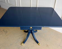 Load image into Gallery viewer, Classic Federal-inspired styling meets a fresh designer finish in this beautifully restored vintage drop leaf table. Professionally lacquered in Sherwin-Williams Naval, this versatile piece features two drop leaves that transform it from a slim console into a generous dining, game, or entry table in seconds. A single center drawer provides convenient storage, while the freshly painted lion head ring pull and polished brass claw feet add timeless elegance and character. Good Bones Furniture