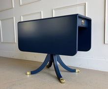 Load image into Gallery viewer, Classic Federal-inspired styling meets a fresh designer finish in this beautifully restored vintage drop leaf table. Professionally lacquered in Sherwin-Williams Naval, this versatile piece features two drop leaves that transform it from a slim console into a generous dining, game, or entry table in seconds. A single center drawer provides convenient storage, while the freshly painted lion head ring pull and polished brass claw feet add timeless elegance and character. Good Bones Furniture