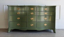 Load image into Gallery viewer, This vintage mahogany dresser makes a strong statement with its elegant serpentine front and generous twelve-drawer layout. The shaped case gives the piece movement and softness, while the symmetrical drawer configuration keeps the overall look balanced and refined. Professionally lacquered in Farrow & Ball Bancha, the finish brings a rich olive green depth that feels classic, tailored, and quietly dramatic. Good Bones Furniture