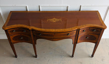 Load image into Gallery viewer, This vintage mahogany sideboard features graceful serpentine lines and exquisite satinwood inlay that highlight its timeless Federal-inspired design. The shaped top showcases a delicate inlaid urn motif, while bowed drawer fronts and paneled cabinet doors add depth and character throughout. A center drawer is flanked by two drawers above spacious side cabinets, providing generous storage for dining essentials or entertaining pieces. Good Bones Furniture