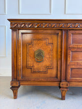 Load image into Gallery viewer, This vintage Mediterranean/ Spanish Revival credenza dresser has the scale, craftsmanship, and presence that make 1970s American case goods so collectible. The design features a carved scrolling frieze, burl veneer door panels, architectural legs, and original brass ring hardware with geometric backplates. Good Bones Furniture