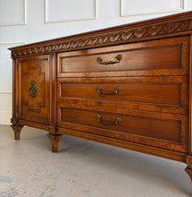 Load image into Gallery viewer, This vintage Mediterranean/ Spanish Revival credenza dresser has the scale, craftsmanship, and presence that make 1970s American case goods so collectible. The design features a carved scrolling frieze, burl veneer door panels, architectural legs, and original brass ring hardware with geometric backplates. Good Bones Furniture