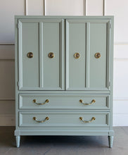 Load image into Gallery viewer, This vintage Thomasville armoire professionally lacquered in a custom muted green with soft blue-gray undertones, while the interior is finished in French Roast. Four paneled doors open to reveal divided upper compartments and two pull-out tray drawers. Two spacious lower drawers offer additional concealed storage. Good Bones Furniture