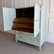 Load image into Gallery viewer, This vintage Thomasville armoire professionally lacquered in a custom muted green with soft blue-gray undertones, while the interior is finished in French Roast. Four paneled doors open to reveal divided upper compartments and two pull-out tray drawers. Two spacious lower drawers offer additional concealed storage. Good Bones Furniture
