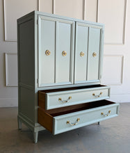 Load image into Gallery viewer, This vintage Thomasville armoire professionally lacquered in a custom muted green with soft blue-gray undertones, while the interior is finished in French Roast. Four paneled doors open to reveal divided upper compartments and two pull-out tray drawers. Two spacious lower drawers offer additional concealed storage. Good Bones Furniture