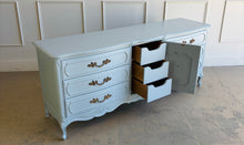 Load image into Gallery viewer, This vintage Thomasville dresser has been professionally lacquered in Farrow & Ball Parma Gray, a soft blue-gray finish that gives its French Provincial styling a fresh, updated look. The piece features a serpentine front, cabriole legs, ornate carved detailing, and original patinaed hardware that adds warmth and character. Good Bones Furniture