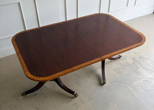 Load image into Gallery viewer, Classic proportions and refined craftsmanship give this vintage banded mahogany dining table its timeless appeal. The rich mahogany top is framed by a contrasting banded edge that adds subtle visual definition, while the double pedestal base brings balance, elegance, and stability. Carved pedestal details and brass-capped feet. Good Bones Furniture