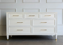 Load image into Gallery viewer, This vintage dresser by Kindel Furniture blends heirloom craftsmanship with a fresh, tailored update. Professionally lacquered in Benjamin Moore White Dove, the finish gives the piece a soft, warm white presence that feels crisp without feeling stark. Fluted corner posts add subtle classical detail, while slim brass bar pulls and brass-capped feet introduce a refined modern contrast. Good Bones Furniture