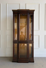 Load image into Gallery viewer, This vintage curio cabinet is a tall, architectural display piece designed to show off collections without overwhelming a room. A narrow footprint makes it an easy fit for dining rooms, living spaces, or entryways, while the glass-front design and interior light create a true “gallery” effect. Glass shelving and framed panels keep the silhouette light and refined, and the substantial crown and stepped base give it a classic, furniture-quality presence.