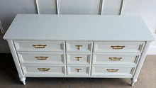 Load image into Gallery viewer, This vintage 7 drawer dresser by White Furniture Co. pairs quality construction with a clean, updated finish. Lacquered in Benjamin Moore White Dove, the soft creamy white highlights the layered drawer molding and tapered turned legs. The original hardware has been painted gold. Good Bones Furniture