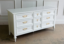 Load image into Gallery viewer, This vintage 7 drawer dresser by White Furniture Co. pairs quality construction with a clean, updated finish. Lacquered in Benjamin Moore White Dove, the soft creamy white highlights the layered drawer molding and tapered turned legs. The original hardware has been painted gold. Good Bones Furniture