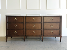 Load image into Gallery viewer, Solid mahogany 9-drawer dresser with brass hardware, styled in a light-filled bedroom