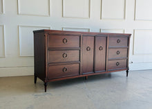 Load image into Gallery viewer, Left front angled view of the Boylan 9 drawer credenza dresser showcasing tapered legs and balanced drawer layout.