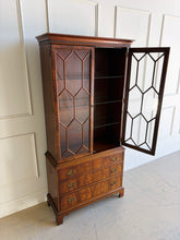 Load image into Gallery viewer, A true heirloom piece from Hickory Chair, this cabinet showcases everything that defines high-end traditional furniture—exceptional materials, precise craftsmanship, and timeless design. The case is wrapped in beautifully bookmatched crotch mahogany veneer, creating dramatic movement across the drawer fronts, while the glazed doors feature geometric muntins that give the piece a tailored, architectural feel. Good Bones Furniture