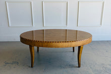 Load image into Gallery viewer, Lillian August oval coffee table in warm wood finish with subtle inlay banding and gently tapered legs, transitional showroom sample in good condition.