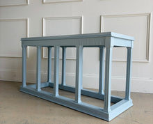 Load image into Gallery viewer, Angled left view of a neoclassical console table finished in Farrow & Ball Parma Gray, showing its sculptural base and modern, architectural silhouette.
