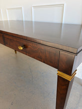 Load image into Gallery viewer, Angled close-up from above showing the left side of the Theodore Alexander Bradbury Desk, emphasizing figured khaya wood grain, top surface, and brass accents at Good Bones Furniture in Raleigh, NC.