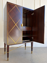 Load image into Gallery viewer, Detail view of the Theodore Alexander Max bar cabinet focusing on the square tapered legs with brass X stretcher base and right door open to interior storage.