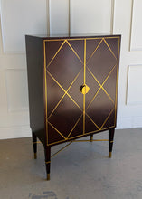 Load image into Gallery viewer, Front angled view of the Theodore Alexander Max bar cabinet featuring mahogany parquet doors with geometric brass diamond trim and half moon brass handles at Good Bones Furniture in Raleigh, North Carolina