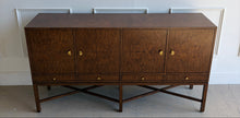 Load image into Gallery viewer, Angled view of Basil Sideboard showcasing symmetrical walnut burl grain across four doors with ginkgo leaf brass hardware and architectural raised base.