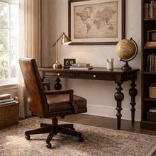 Load image into Gallery viewer, Home office view of the Vivienne Desk in Teak Brown finish by Bramble, a mahogany writing desk with sculptural turned legs and two drawers, crafted in Indonesia and offered by Good Bones Furniture to customers across the United States.
