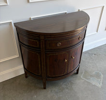 Load image into Gallery viewer, The Demilune Cabinet by Ambella Home combines graceful curves with richly figured wood veneer and classical detailing. Antiqued gold accents outline the drawer, doors, architectural panels, and tapered legs, emphasizing the cabinet’s rounded silhouette. A spacious upper drawer with decorative ring pulls provides convenient storage for smaller essentials, while two curved doors open to reveal an interior shelf for larger items. Good Bones Furniture
