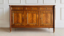 Load image into Gallery viewer,  A study in balance and material, the Riley Sideboard draws from European neoclassical design—most notably Louis XVI—reimagined through a quieter, more modern lens. The form is clean and architectural, defined by symmetry, framed panels, and gently tapered legs that give the piece a sense of structure without excess. Cerejeira veneers are carefully bookmatched across each door, revealing a striking cathedral grain that brings movement and depth to the façade. Good Bones Furniture
