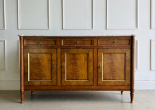 Load image into Gallery viewer,  A study in balance and material, the Riley Sideboard draws from European neoclassical design—most notably Louis XVI—reimagined through a quieter, more modern lens. The form is clean and architectural, defined by symmetry, framed panels, and gently tapered legs that give the piece a sense of structure without excess. Cerejeira veneers are carefully bookmatched across each door, revealing a striking cathedral grain that brings movement and depth to the façade. Good Bones Furniture
