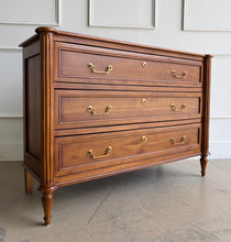 Load image into Gallery viewer, Gently used Ciborium chest by Sarreid showcases timeless European-inspired styling and exceptional craftsmanship. Constructed of solid walnut with a warm fruitwood finish, the piece features fluted corner columns, tapered turned legs, and three generously sized drawers accented with classic brass pulls and decorative faux keyhole escutcheons. Good Bones Furniture
