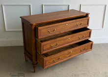 Load image into Gallery viewer, Gently used Ciborium chest by Sarreid showcases timeless European-inspired styling and exceptional craftsmanship. Constructed of solid walnut with a warm fruitwood finish, the piece features fluted corner columns, tapered turned legs, and three generously sized drawers accented with classic brass pulls and decorative faux keyhole escutcheons. Good Bones Furniture
