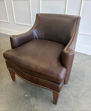 Load image into Gallery viewer, The Bentley Hall Leather Lounge Chair by Fairfield Chair combines rich materials, architectural lines, and exceptional comfort. Upholstered in deep chocolate brown leather, its sculptural tight back flows into sweeping arms outlined with antique brass nailhead trim. An ultra-plush loose seat cushion and high-resiliency back create an inviting place to relax, while arched spring construction provides lasting support. Tapered wood legs complete the timeless silhouette. Good Bones Furniture
