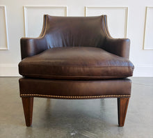 Load image into Gallery viewer, The Bentley Hall Leather Lounge Chair by Fairfield Chair combines rich materials, architectural lines, and exceptional comfort. Upholstered in deep chocolate brown leather, its sculptural tight back flows into sweeping arms outlined with antique brass nailhead trim. An ultra-plush loose seat cushion and high-resiliency back create an inviting place to relax, while arched spring construction provides lasting support. Tapered wood legs complete the timeless silhouette. Good Bones Furniture
