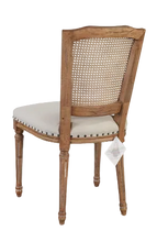 Load image into Gallery viewer, The Ellen Side Chair combines timeless European-inspired detailing with everyday durability. Crafted from solid mango wood, its distressed Beachwood finish highlights the carved frame, turned legs, and warm natural character of the wood. A handwoven cane back adds airy texture, while the upholstered seat is finished with classic nailhead trim. Sand Revolution Performance Fabric. Good Bones Furniture
