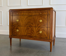 Load image into Gallery viewer, The Lipton 3 Drawer Chest brings classic European character. Crafted from mahogany solids with bookmatched cerejeira veneers, the drawer fronts showcase a dramatic cathedral grain that gives the piece warmth and movement. Fluted corner details, a carved lower border, tapered legs, and decorative brass hardware complete its tailored silhouette. Three spacious drawers on soft close glides. Good Bones Furniture
