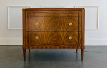 Load image into Gallery viewer, The Lipton 3 Drawer Chest brings classic European character. Crafted from mahogany solids with bookmatched cerejeira veneers, the drawer fronts showcase a dramatic cathedral grain that gives the piece warmth and movement. Fluted corner details, a carved lower border, tapered legs, and decorative brass hardware complete its tailored silhouette. Three spacious drawers on soft close glides. Good Bones Furniture
