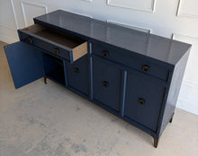 Load image into Gallery viewer, This like-new Hekman sideboard has been professionally refinished in a custom dark Sherwin Williams Naval lacquer, creating a rich, sophisticated finish that highlights the cabinet's clean lines and subtle oak grain texture. Antiqued brass hardware and a matching brass base add warmth and contrast, giving the piece a tailored, designer-inspired look. Good Bones Furniture
