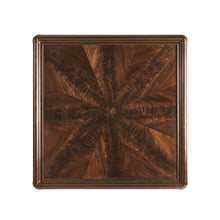 Load image into Gallery viewer, Hickory White Carmen Cocktail Table offered  by Good Bones Furniture. Crafted from walnut solids and crotch walnut veneers, the square top showcases dramatic figuring that radiates from the center, creating movement and sophistication across the surface. Brass metal accents wrap the upper legs and form a sleek stretcher base, introducing a tailored architectural element that balances the warmth of the walnut.
