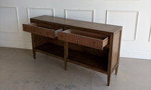 Load image into Gallery viewer, The Hickory White Tulia Console combines tailored craftsmanship with warm natural character. Finished in the rich Autumn finish, the wood grain is beautifully highlighted across the top and case, giving the piece a relaxed but refined presence. The design features two fluted-front drawers with small brass knobs, paired with open shelving below for additional storage or display. Good Bones Furniture
