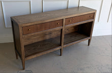 Load image into Gallery viewer, The Hickory White Tulia Console combines tailored craftsmanship with warm natural character. Finished in the rich Autumn finish, the wood grain is beautifully highlighted across the top and case, giving the piece a relaxed but refined presence. The design features two fluted-front drawers with small brass knobs, paired with open shelving below for additional storage or display. Good Bones Furniture
