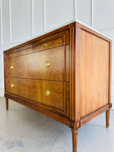 Load image into Gallery viewer, The Lipton Accent Chest is an exquisite blend of classic design and modern luxury. Crafted from mahogany solids with cerejeira and mahogany veneers, this piece showcases a stunning, highly figured grain pattern framed by elegant fluted corner details. The smooth white marble top or luxurious mahogany top adds a timeless sophistication and practical durability, making this chest as functional as it is beautiful. Good Bones Furniture
