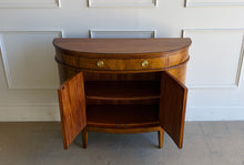 Load image into Gallery viewer, The Lipton Demilune Cabinet is a refined storage piece with a softly curved, architectural silhouette. Crafted from mahogany solids with cerejeira veneers, it showcases a flowing, bookmatched grain pattern across the rounded front for a warm, elevated look. Good Bones Furniture
