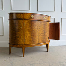 Load image into Gallery viewer, The Lipton Demilune Cabinet is a refined storage piece with a softly curved, architectural silhouette. Crafted from mahogany solids with cerejeira veneers, it showcases a flowing, bookmatched grain pattern across the rounded front for a warm, elevated look. Good Bones Furniture
