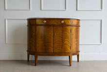 Load image into Gallery viewer, The Lipton Demilune Cabinet is a refined storage piece with a softly curved, architectural silhouette. Crafted from mahogany solids with cerejeira veneers, it showcases a flowing, bookmatched grain pattern across the rounded front for a warm, elevated look. Good Bones Furniture
