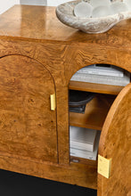 Load image into Gallery viewer, The Modern History Arches Credenza is a striking statement piece defined by rich material and architectural form. Wrapped in dramatic Ashe burl veneer, the surface reveals intricate swirling grain patterns that create depth and visual movement across the entire façade. A sequence of softly arched doors gives the cabinet its signature rhythm, adding sculptural interest while maintaining a clean, tailored silhouette. Good Bones Furniture
