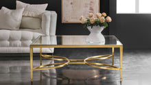 Load image into Gallery viewer, The Modern History Brielle Cocktail Table pairs clean lines with sculptural detail for a refined, airy centerpiece. Its polished brass frame is accented by an elegant stretcher in a flowing quatrefoil-inspired pattern that adds movement and visual interest beneath the glass top. The tempered clear glass surface keeps the silhouette light and open, allowing the brass framework to remain the focal point. Good Bones Furniture
