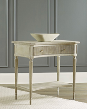 Load image into Gallery viewer, The Modern History Ribbed Bedside Table combines understated elegance with functional design. Finished in a serene painted antique grey, this piece features a subtly ribbed texture that adds depth and visual interest. Its single drawer, adorned with polished brass hardware, offers convenient storage while enhancing the table's classic charm.
