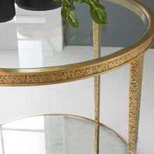 Load image into Gallery viewer, The Modern History Sculpture Round Table pairs bold texture with clean modern lines. Crafted with a richly textured antique brass finish, the circular frame has a sculptural presence that adds warmth and visual depth to a living space. A clear glass top keeps the design light and airy while showcasing the distinctive hammered brass detailing. Good Bones Furniture
