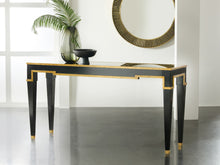Load image into Gallery viewer, The Modern History Sparro Console blends strong architectural lines with refined materials. Its sleek silhouette is finished in deep ebony paint and highlighted with gold leaf striping that frames the piece with subtle geometric detail. The contrast between the dark finish and warm gold accents creates a sophisticated, gallery-like presence. Good Bones Furniture

