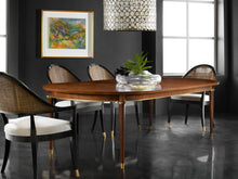 Load image into Gallery viewer, The Norris Dining Table by Modern History blends refined craftsmanship with understated glamour. Crafted in hand-rubbed walnut veneer, the table showcases a warm, richly toned surface that highlights the natural beauty of the wood grain. A sculptural apron accented with gold leaf detailing adds subtle luminosity beneath the tabletop, while slender tapered legs finished with brass ferrules provide an elegant finishing touch. Good Bones Furniture
